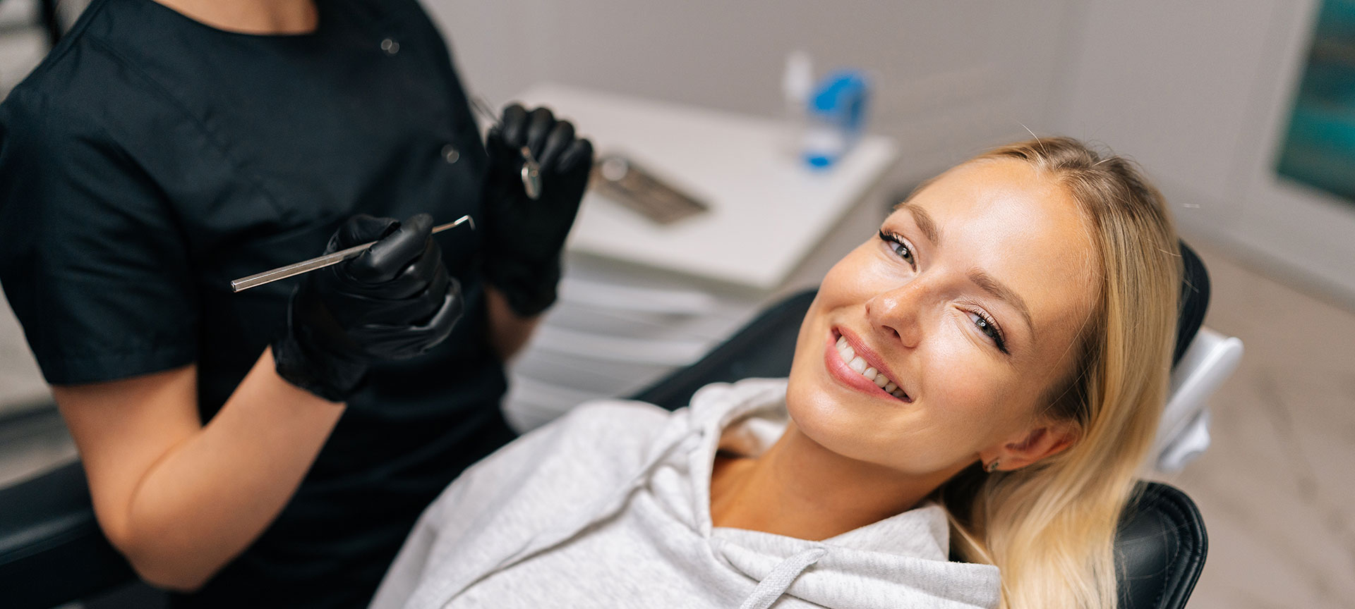 Woman in a hair salon, smiling, with a hairstylist cutting her hair.