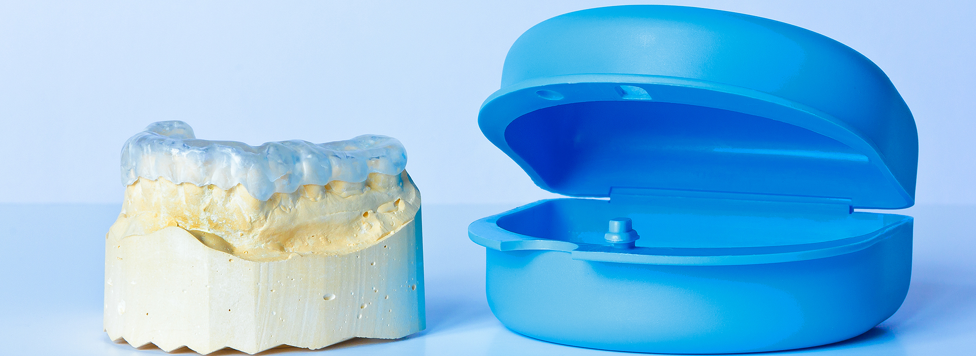 The image shows a blue dental impression tray next to a yellow resin model, which appears to be a 3D printed representation of a tooth and its surrounding gumline.